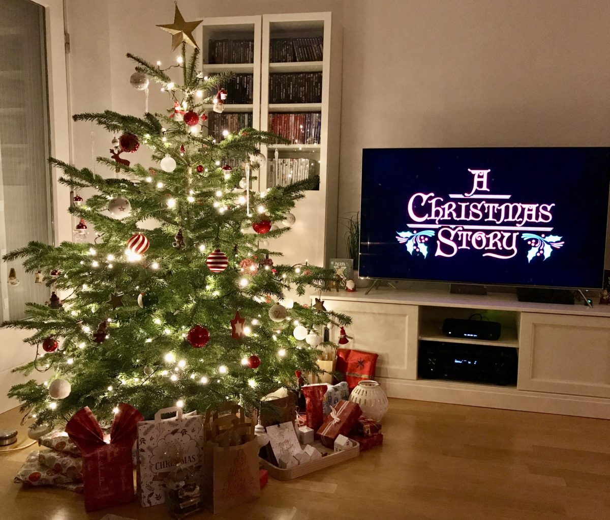 Ein Weihnachtsbaum in einem Wohnzimmer mit Fernseher.