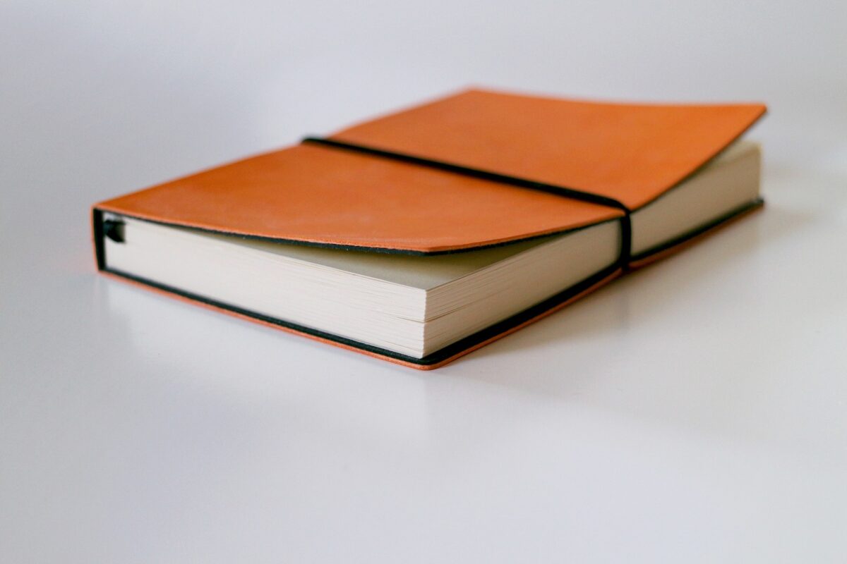 Ein orangefarbenes Ledertagebuch auf einer weißen Oberfläche.